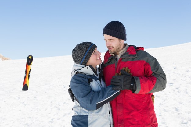 Feliz pareja amorosa con tabla de esquí en la nieve en el fondo