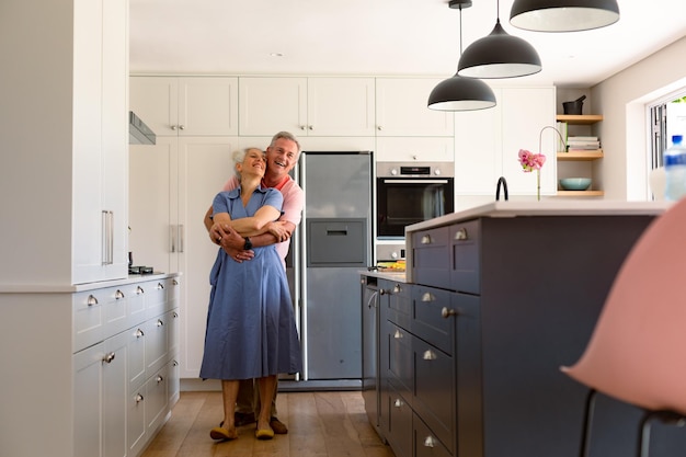 Foto feliz pareja de ancianos caucásicos bailando juntos en la cocina y divirtiéndose