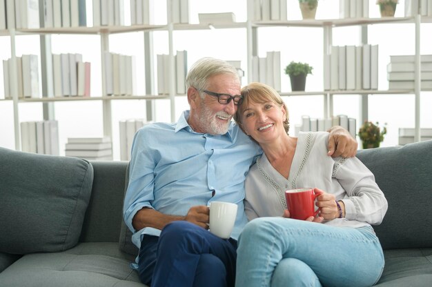 Feliz pareja de ancianos caucásicos está bebiendo café en casa, relajante y concepto de atención médica.