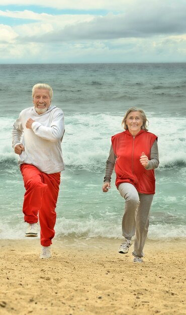 Feliz pareja de ancianos corriendo en una playa