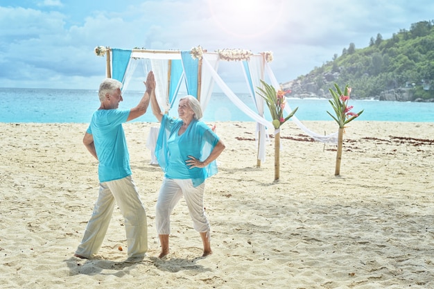 Feliz pareja de ancianos descansa en la playa tropical