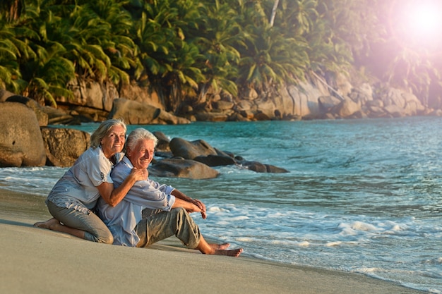 Feliz pareja de ancianos descansa en la playa tropical