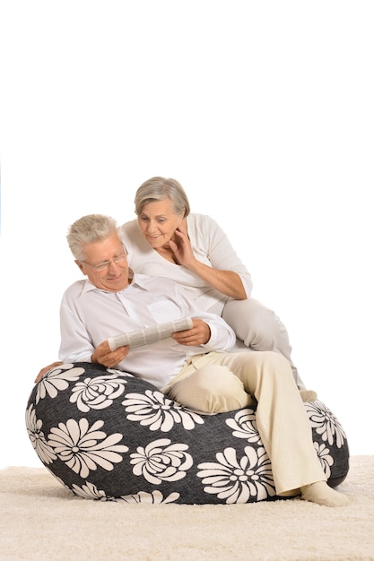 Feliz pareja de ancianos descansando, sentado en una silla y leyendo el periódico