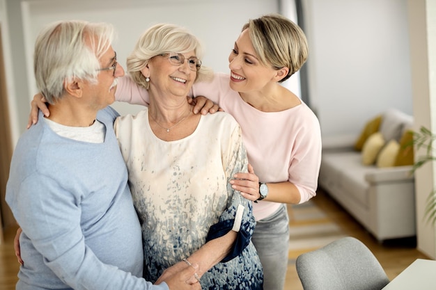 Feliz pareja de ancianos hablando con su hija adulta en casa