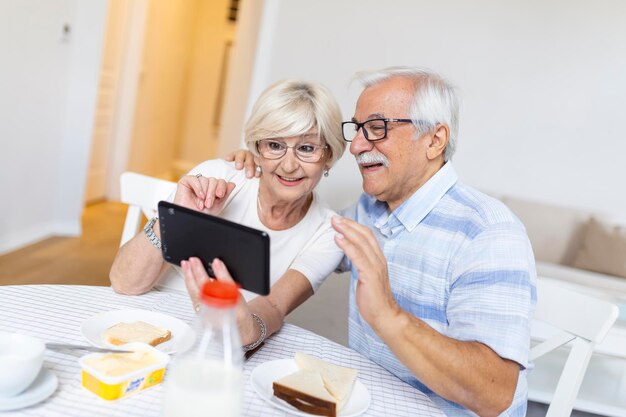 Una feliz pareja de ancianos hablando con sus nietos usando una tableta sorprendió a una anciana emocionada mirando una tableta saludando y sonriendo