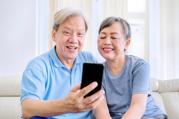 Feliz pareja de ancianos haciendo una videollamada en casa