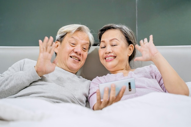 Feliz pareja de ancianos haciendo videollamadas con su nieto