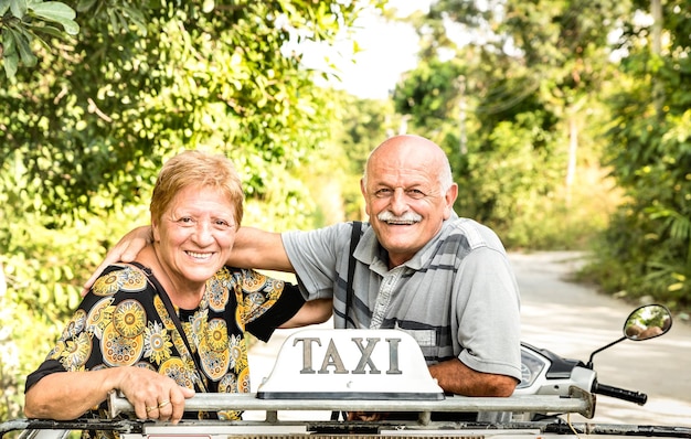 Feliz pareja de ancianos jubilados tomando una foto de viaje en un tour de scooter en taxi