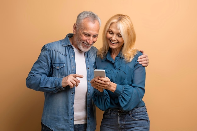 Feliz pareja de ancianos mirando la pantalla del teléfono inteligente usando una aplicación móvil