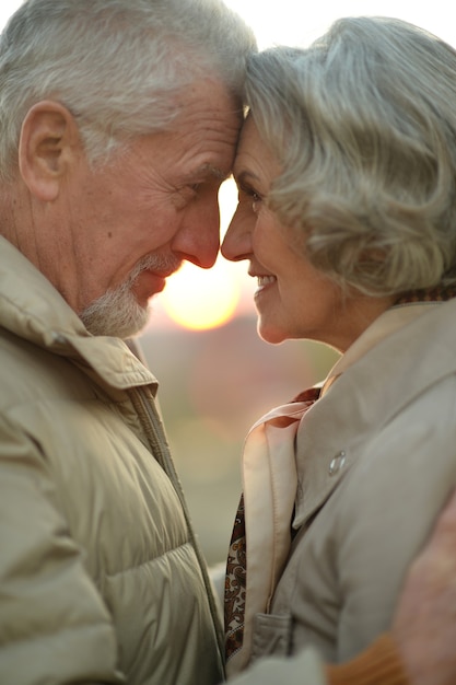 Feliz pareja de ancianos en la naturaleza en el fondo del atardecer