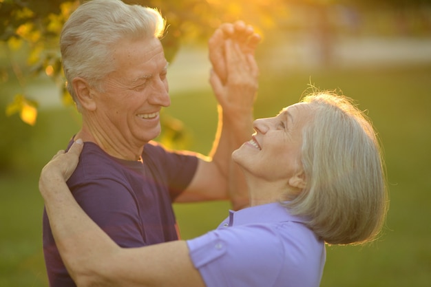 Feliz pareja de ancianos en la naturaleza en el fondo del atardecer