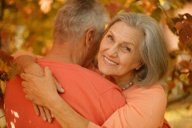 Feliz pareja de ancianos posando en el parque de otoño