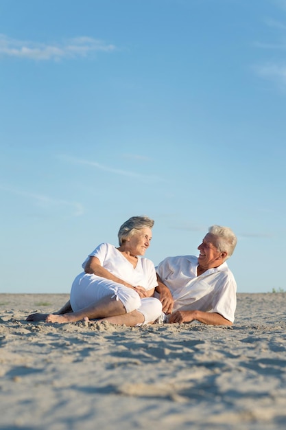 Feliz pareja de ancianos sentados en la arena