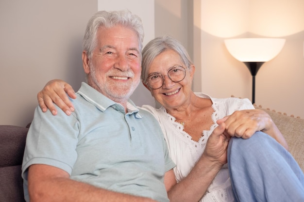 Foto una feliz pareja de ancianos sentados en el sofá mirando a la cámara recordando buenos recuerdos.
