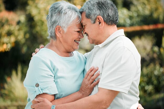 Feliz pareja de ancianos se tocan y se abrazan en el jardín del parque y la paz del cuidado, la felicidad y el amor juntos El anciano, la mujer y la jubilación del compañero matrimonial se relajan o sonríen de tiempo de calidad en la naturaleza