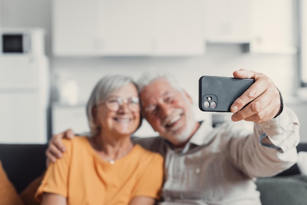 Feliz pareja de ancianos tomándose selfie en el teléfono celular sonriendo cónyuges maduros esposa de mediana edad y esposo jubilado riéndose sosteniendo el teléfono hacen autorretrato en la cámara del teléfono inteligente enfocada en la pantalla móvilxA