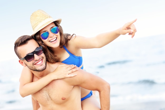 feliz pareja apuntando a algo en la playa