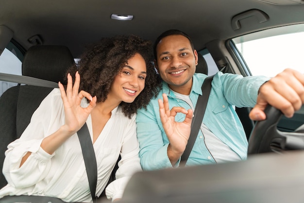 Feliz pareja árabe disfrutando del viaje en auto dando un gesto positivo de acuerdo