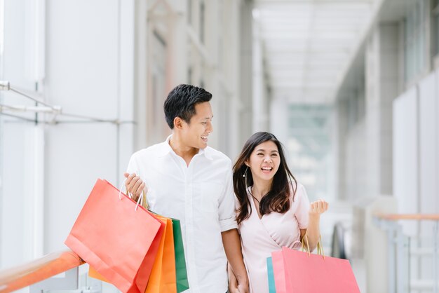 Feliz pareja asiática disfruta de ir de compras en el centro comercial