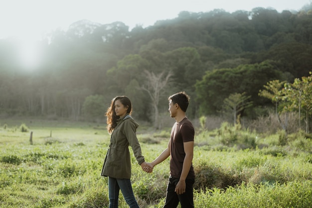 Feliz pareja asiática joven en campo disfrutando de la naturaleza