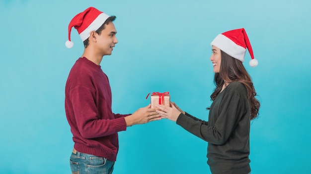 Feliz pareja asiática joven sosteniendo cajas de regalo de Navidad con cara sonriente feliz aislado en azul
