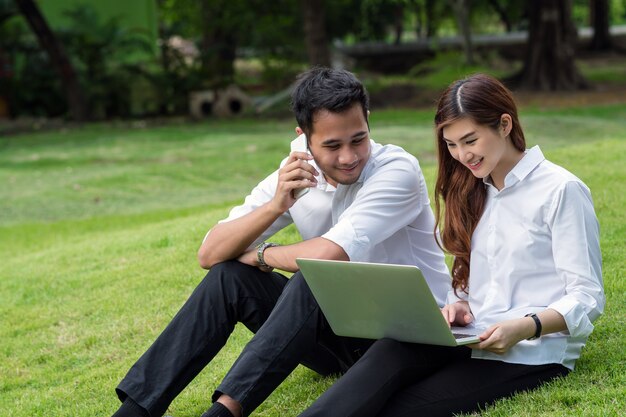 Feliz pareja asiática universidad trabajando a través de tecnología portátil