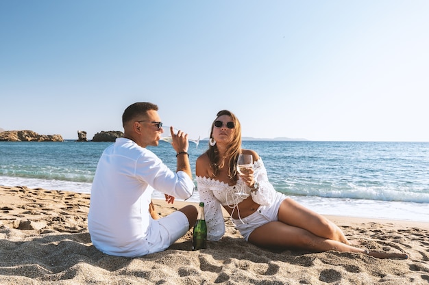 Feliz pareja de asientos con champán en la playa