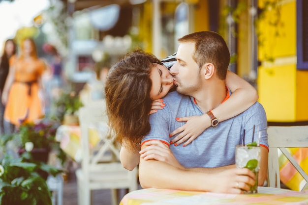 Feliz pareja bebiendo limonada en un café exterior.