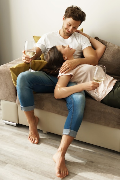 Feliz pareja bebiendo vino y relajándose en casa