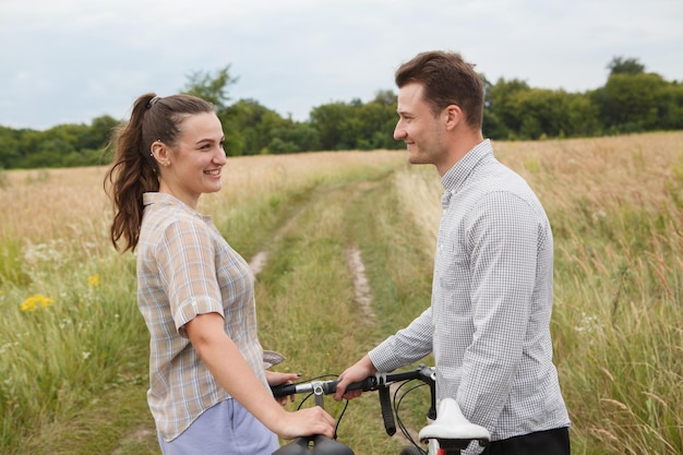 La feliz pareja en bicicleta cerca del campo.