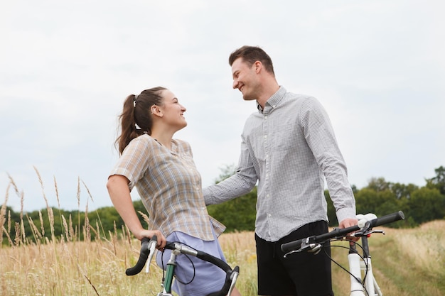 La feliz pareja en bicicleta cerca del campo.