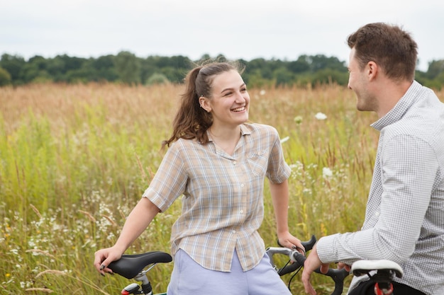 La feliz pareja en bicicleta cerca del campo.