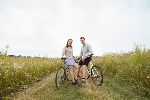 Foto la feliz pareja en bicicleta cerca del campo.