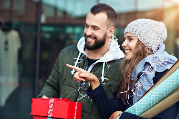 Foto feliz pareja con bolsas de la compra después de ir de compras en la ciudad sonriendo y abrazándose