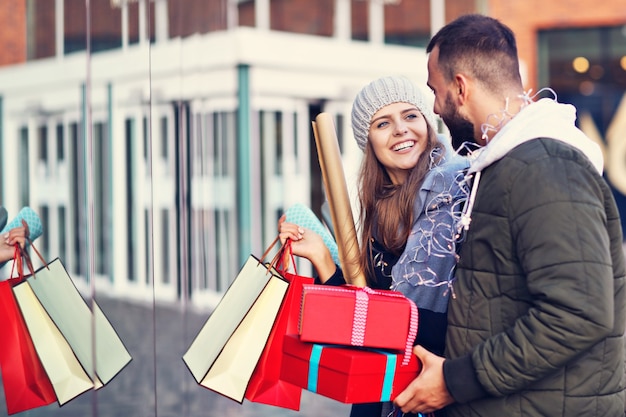 Feliz pareja con bolsas de la compra después de ir de compras en la ciudad sonriendo y abrazándose