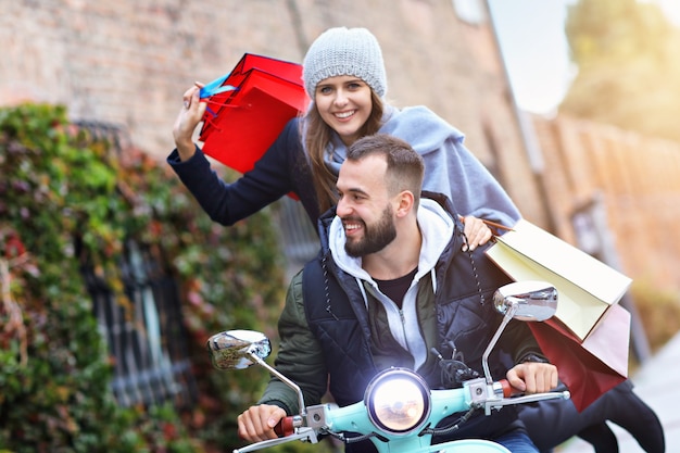 Feliz pareja con bolsas de la compra después de ir de compras en la ciudad sonriendo y abrazándose