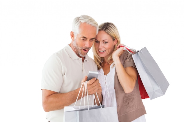 Feliz pareja con bolsas de compras y teléfono inteligente