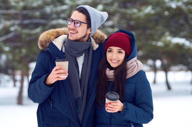 Feliz pareja con café en el bosque de invierno hace selfie. . Feliz invierno. Navidad.