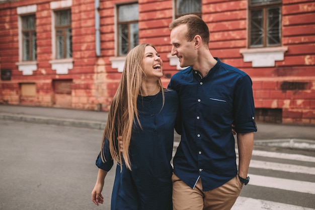 Feliz pareja caminando por el paso de peatones en la ciudad