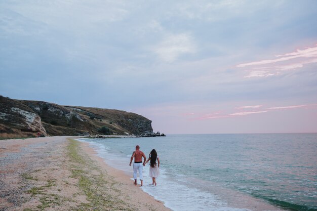 Feliz pareja caminar descalzo en la playa