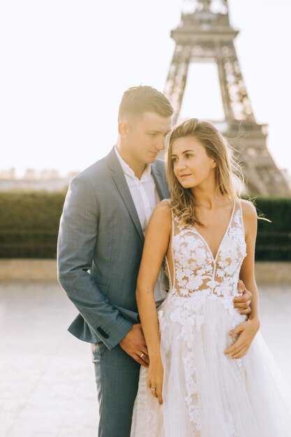 Feliz pareja casada romántica abrazando cerca de la torre Eiffel en París