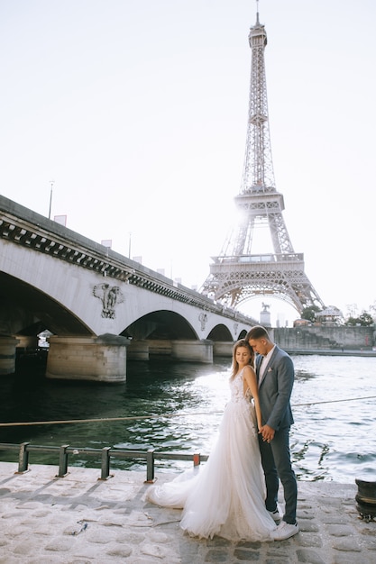 Feliz pareja casada romántica abrazando cerca de la torre Eiffel en París