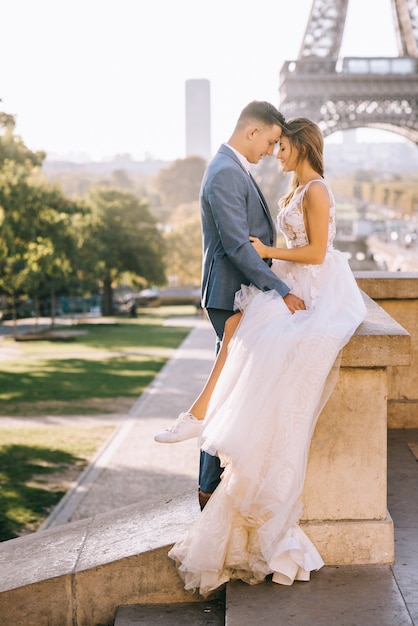 Feliz pareja casada romántica abrazando cerca de la torre Eiffel en París