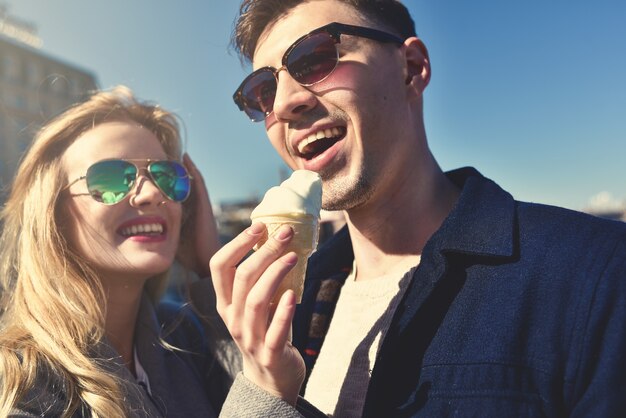 Feliz pareja caucásica romántica en gafas de sol. Chica divertida come el helado