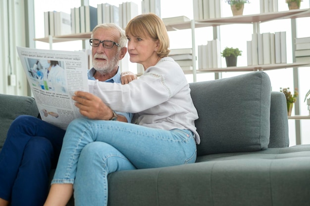 Feliz pareja caucásica senior son relajantes, leyendo el periódico en la sala de estar