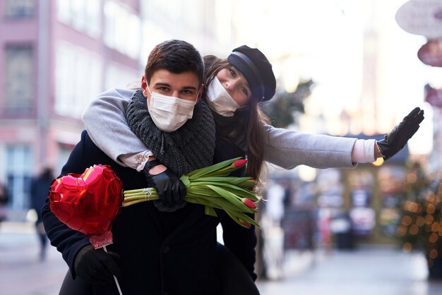 Feliz pareja celebrando el día de San Valentín en máscaras durante la pandemia de covid-19 en la ciudad