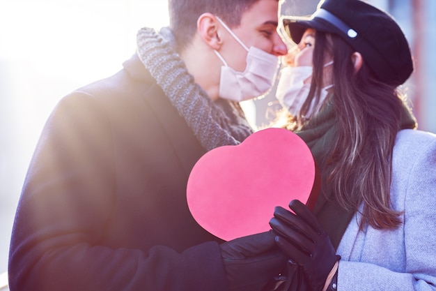 Feliz pareja celebrando el día de San Valentín en máscaras durante la pandemia de covid-19 en la ciudad