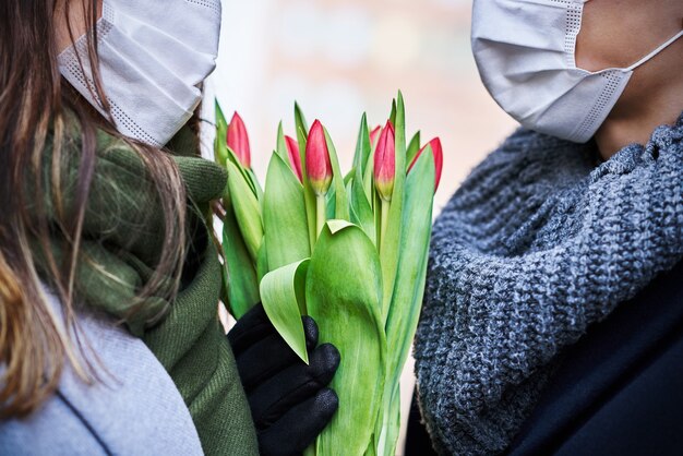 Feliz pareja celebrando el día de San Valentín en máscaras durante la pandemia de covid-19 en la ciudad