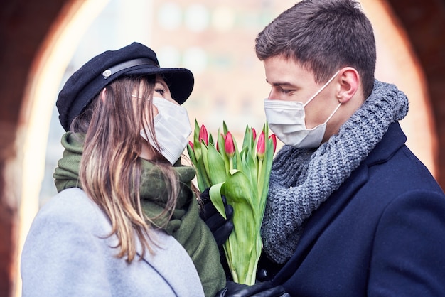 Feliz pareja celebrando el día de San Valentín en máscaras durante la pandemia de covid-19 en la ciudad