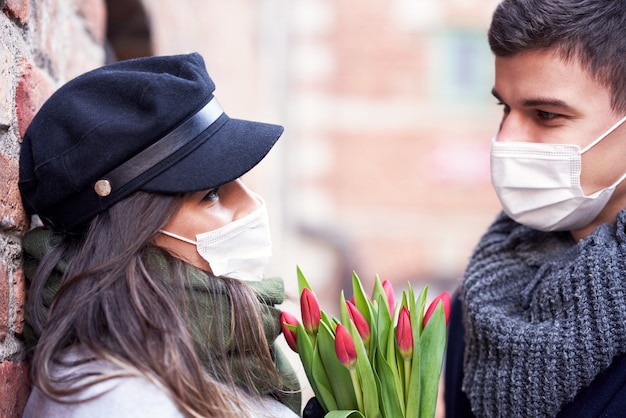 Feliz pareja celebrando el día de San Valentín en máscaras durante la pandemia de covid-19 en la ciudad